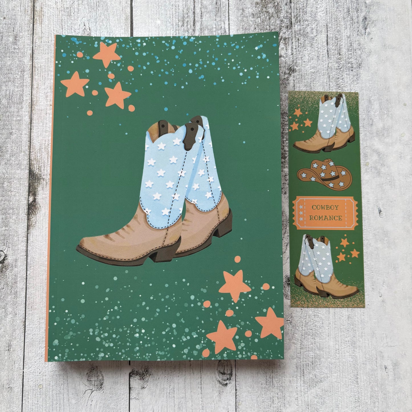 Book journal with cowboy boots and stars on a green background, placed on a wooden surface.