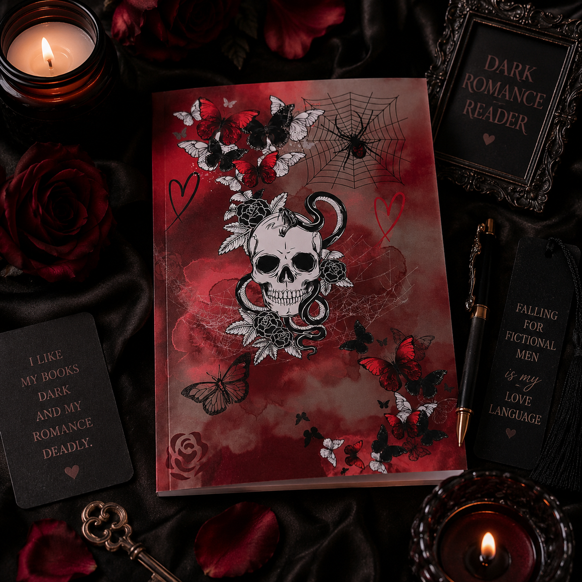 A gothic-themed journal with a skull, roses, and snakeskin print, styled on a black fabric background with candles, roses, and books.