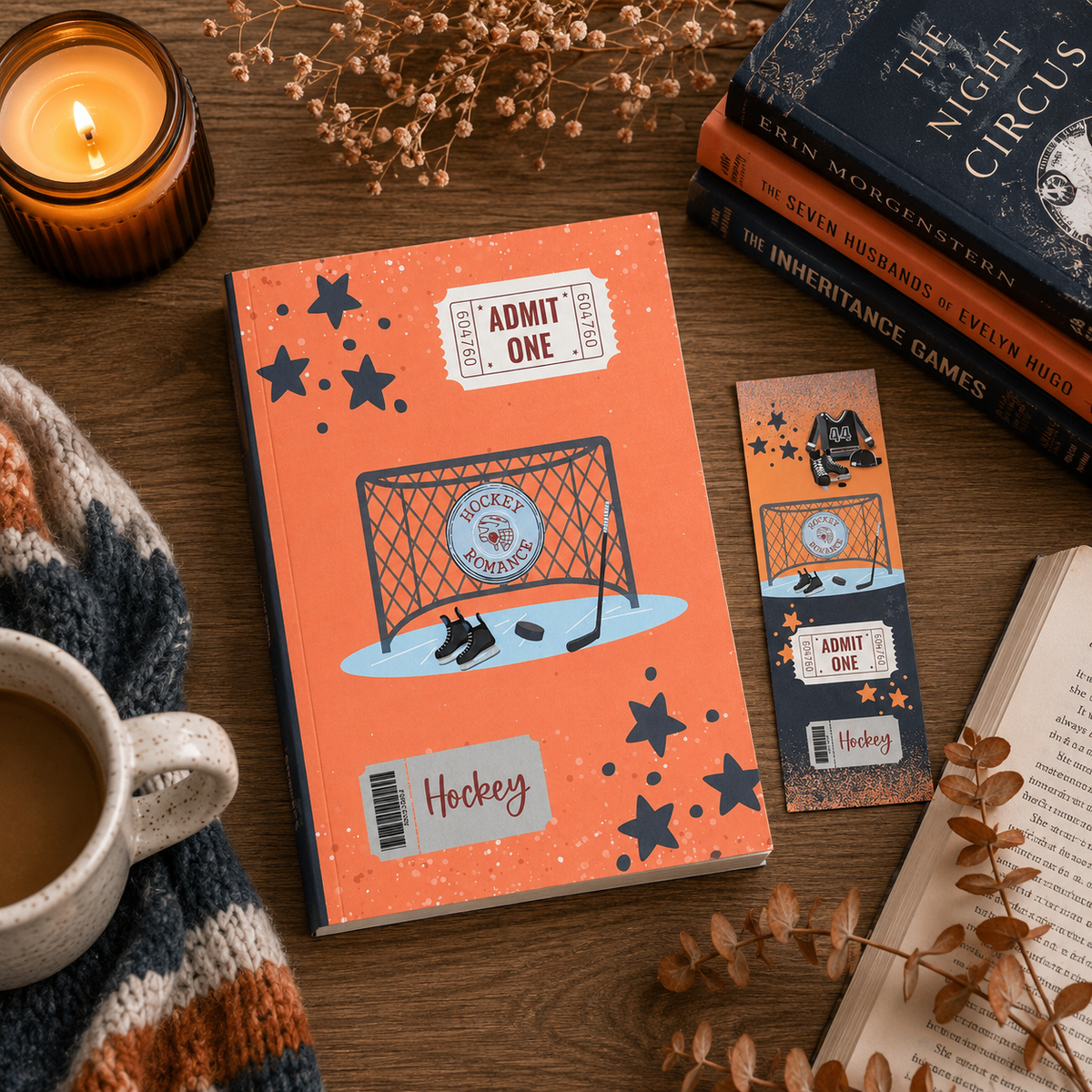 A styled flat-lay featuring a custom hockey-themed journal and matching bookmark on a wooden table, surrounded by cozy props including a lit candle, a mug of tea, a knit blanket, and books.