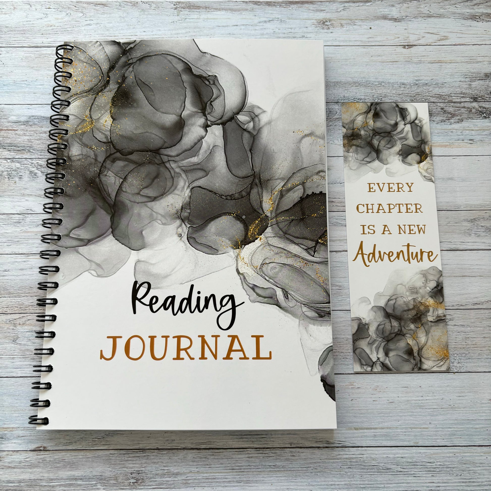 A reading journal and a bookmark with a marble design, placed on a wooden surface.