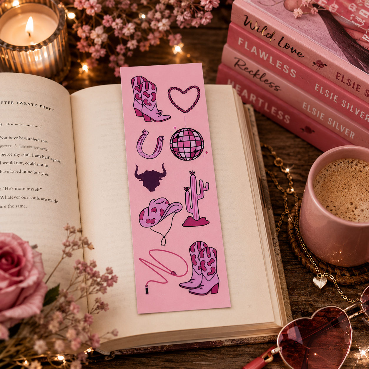 Pink cowboy romance bookmark on an open book with Elsie Silver books on a desk