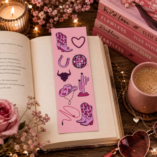 Pink cowboy romance bookmark on an open book with Elsie Silver books on a desk